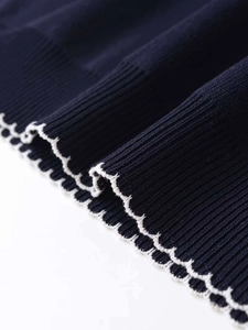 Detail view of navy blue knit sweater featuring delicate white scalloped lace edge trim