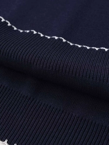 Close-up of navy knit fabric showing ribbed texture and white wavy decorative stitching