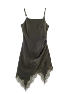 Détail d'une robe en satin vert olive avec dentelle noire délicate et ourlet asymétrique