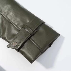 Detail of dark olive green leather coat sleeve with metallic button and fine stitching