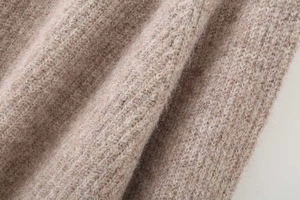Detailed macro view of soft oatmeal knitted fabric texture showing warm wool fibers