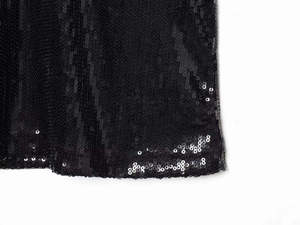 Gros plan détaillé des paillettes noires brillantes sur le tissu de la mini robe licou