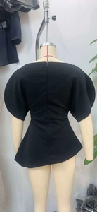 Detailansicht der Rückseite eines schwarzen Schößchen-Tops mit Puffärmeln und Reißverschluss