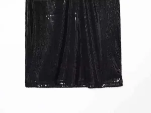 Gros plan du tissu à paillettes noires montrant la texture brillante de la robe dos nu