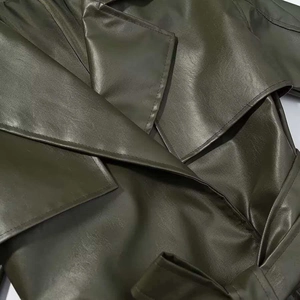 Close-up of olive green PU leather coat showing wide lapels and waist belt detail