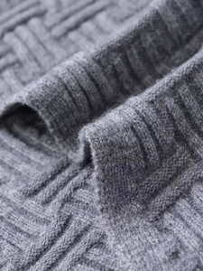 Macro shot of grey geometric knit pattern and ribbed edge texture of the sweater