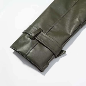Detail of olive green leather coat sleeve featuring decorative strap and stitching