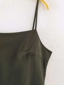 Détail d'une robe en satin vert foncé avec fines bretelles et texture de tissu soyeux