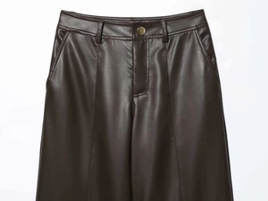 Détails macro du pantalon en similicuir marron foncé avec bouton et plis à la taille