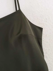 Détail de robe satinée vert foncé avec bretelles spaghetti et texture lisse soyeuse