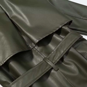 Detail shot of the waist belt and refined leather texture of the olive green trench coat