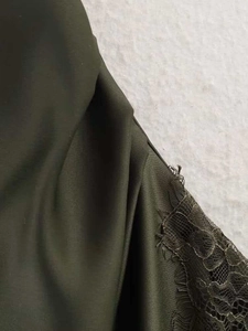 Vue macro détaillée du tissu de la robe vert olive avec dentelle complexe et finition lisse