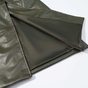 Detail of dark green faux leather coat with smooth satin lining and neat stitching
