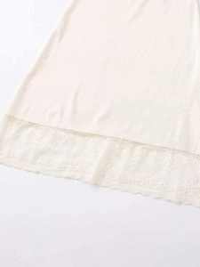 Detailed view of the elegant floral lace hem on a beige summer knit midi skirt