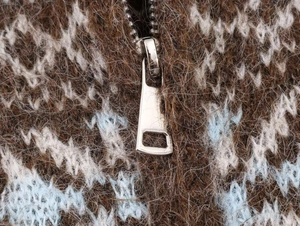 Macro shot of silver metal zipper on vintage jacquard knit mohair sweater in brown and blue