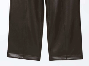 Vue détaillée de la texture du similicuir marron foncé et de l'ourlet cousu du pantalon