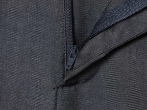 Close-up of high-quality metal zipper detail on dark grey twill dress trousers