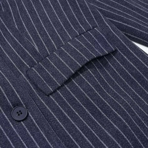 Detail of navy blue pinstripe wool coat featuring a flap pocket and matching resin button
