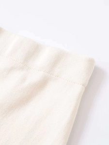 Detail of elastic wide waistband on cream knitted lace skirt showing soft ribbed texture