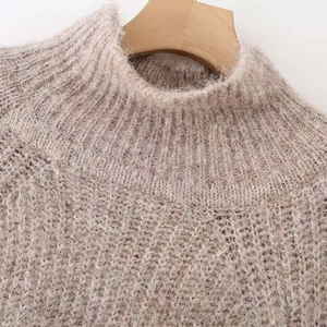 Oatmeal knit sweater with puff sleeves and crew neck texture on a wooden hanger