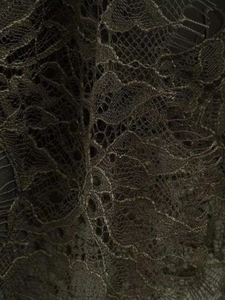 Vue macro de la broderie en dentelle foncée et texture en maille de la robe