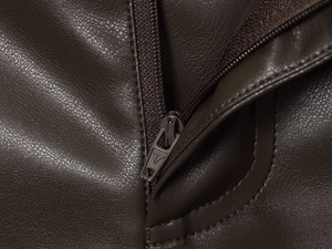 Détail macro de la texture en similicuir marron foncé et fermeture éclair métallique robuste