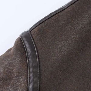 Detailed close-up showing litchi texture and sewing on dark brown leather jacket shoulder