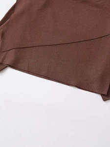 Detail view of coffee brown knit top featuring a unique overlapping asymmetric hemline