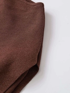 Macro shot of dark brown knit fabric showing fine texture and hem detail on the top