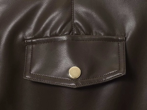 Détail macro de la texture simili cuir marron avec poche à rabat et bouton en métal doré