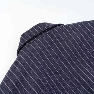 Detailed close-up of navy blue pinstripe wool fabric with precise stitching and texture