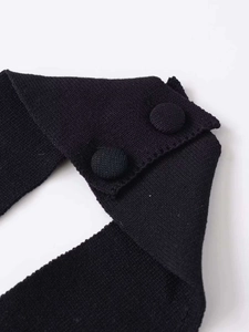 Detail of black knit halter top showing neck strap and fabric covered buttons