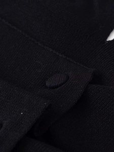Close-up of black knit fabric texture and matching fabric-covered button detail