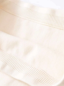 Detail of soft cream knitted fabric with fine ribbing texture and elegant draped folds