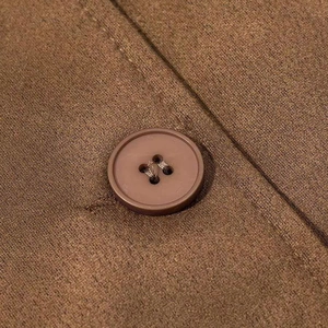 Detailed close-up of brown faux suede fabric texture and matching four-hole resin button