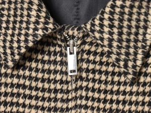 Detail of classic houndstooth jacket featuring a high-quality silver metal zipper and collar