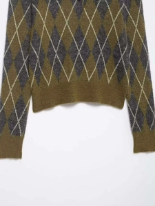 Gros plan sur le motif à losanges et l'ourlet côtelé du polo en tricot olive et gris