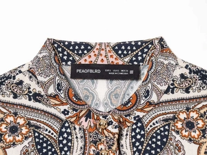 Detail of the paisley print shirt featuring a black brand label and golden ball buttons