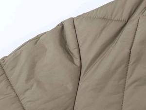 Detail shot of the olive green quilted jacket featuring classic diamond stitching and padding