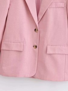Detail of pink blazer featuring amber buttons, notch lapels and fine twill fabric texture
