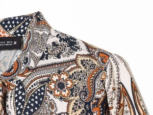 Detail of paisley print blouse collar with size S label and linen-like fabric texture