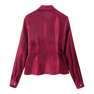 Detail of burgundy satin shirt back view showing smooth glossy texture and waist tie