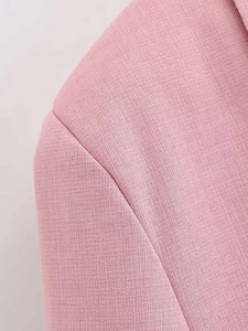 Detailed macro view of light pink blazer showing textured fabric weave and shoulder stitching