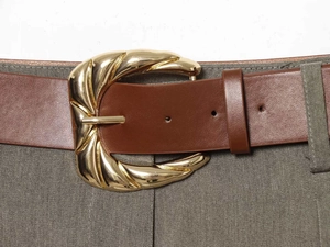 Detail view of a vintage gold-toned sculptural buckle on a dark brown textured waist belt