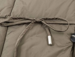 Detailed view of quilted winter jacket fabric with adjustable drawstrings and metallic tips