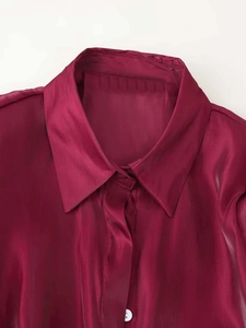 Detail of burgundy satin shirt fabric texture with glossy finish and white button detail