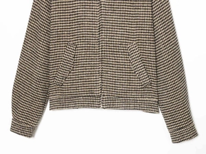 Detail of houndstooth jacket featuring metal zipper and slanted welt side pockets