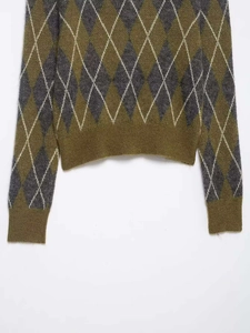 Détail d'un pull en maille à losanges avec poignets et ourlet côtelés vert et gris