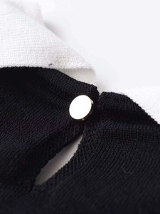 Detail of contrast collar with a golden button on a slim-fit knit sweater for women