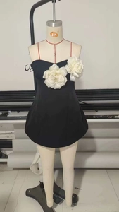 Détail d'une mini robe noire ornée de grandes fleurs blanches en relief sur la poitrine